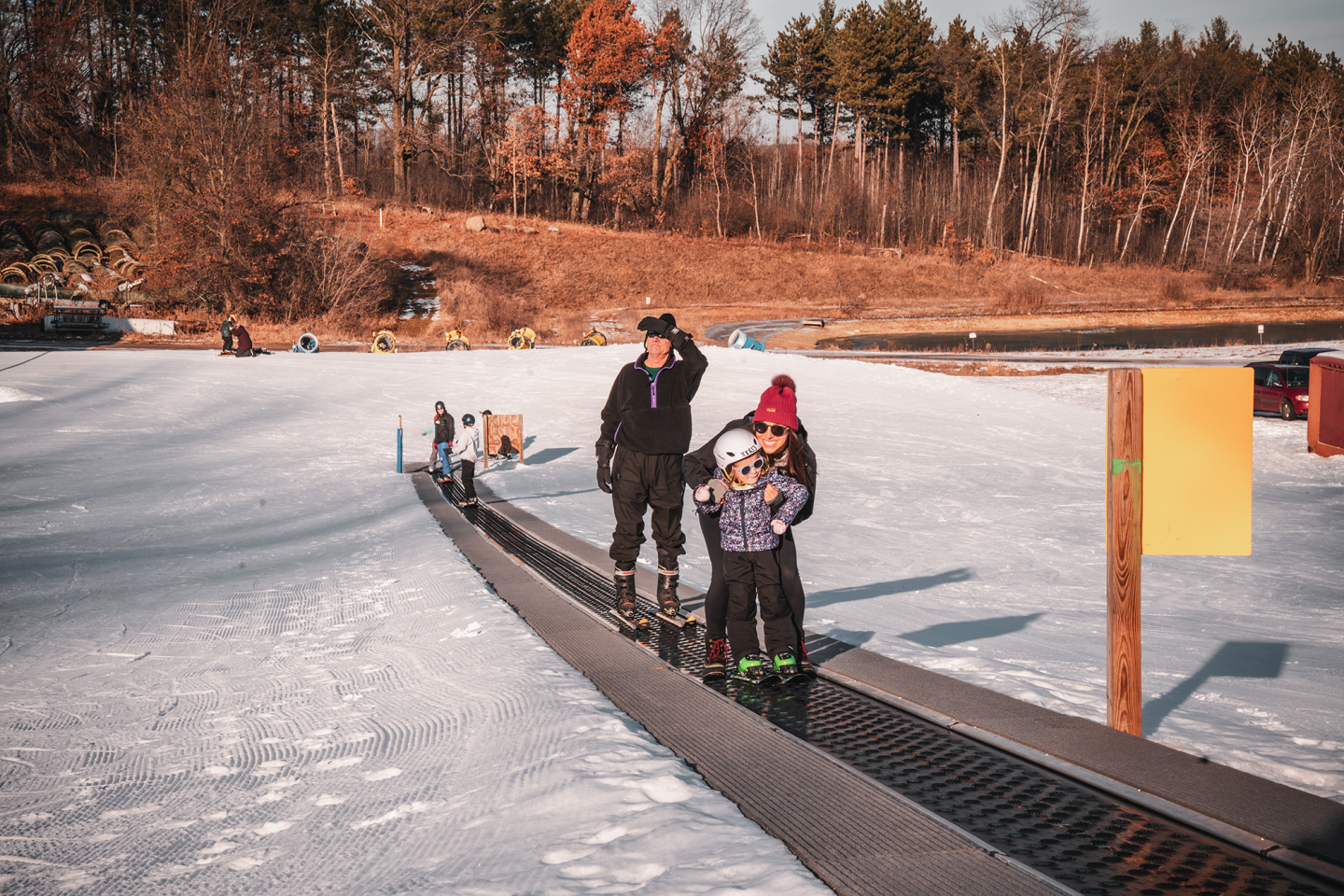 parent and child going up magic carpet on ski hill